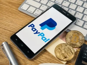 physische Bitcoin Münzen neben einem Smartphone mit PayPal