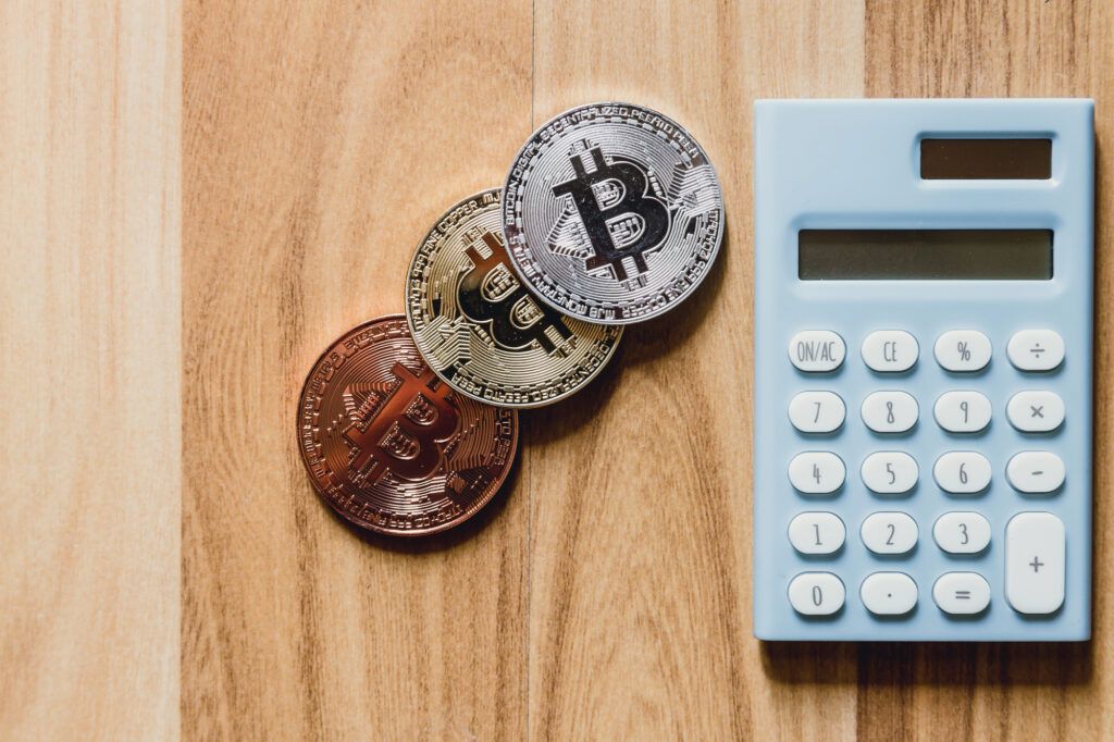 Bitcoin Münzen neben einem Taschenrechner als Bild für die Haltefrist